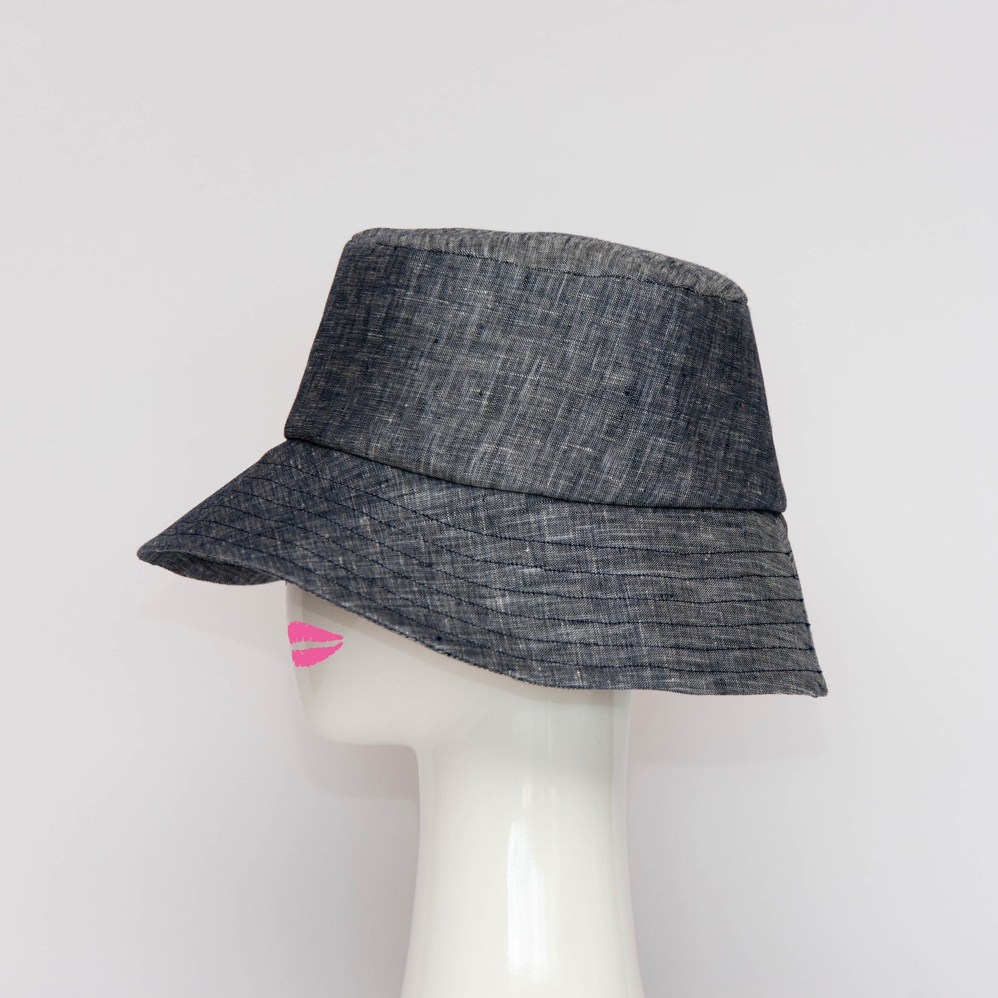 A side view of the Appin Bucket Hat in cotton denim has a square shape crown with tip and side band. Created by Melbourne based Lauren J Ritchie Millinery.