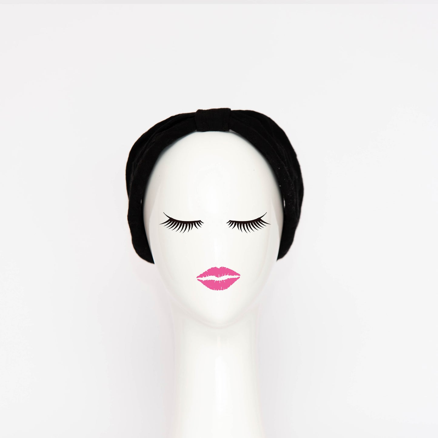 A front view of the Georgie Headband in black. The headband is a hand draped shape that is cinched with a centre wrap. The headpiece is created by Melbourne based Lauren J Ritchie Millinery.