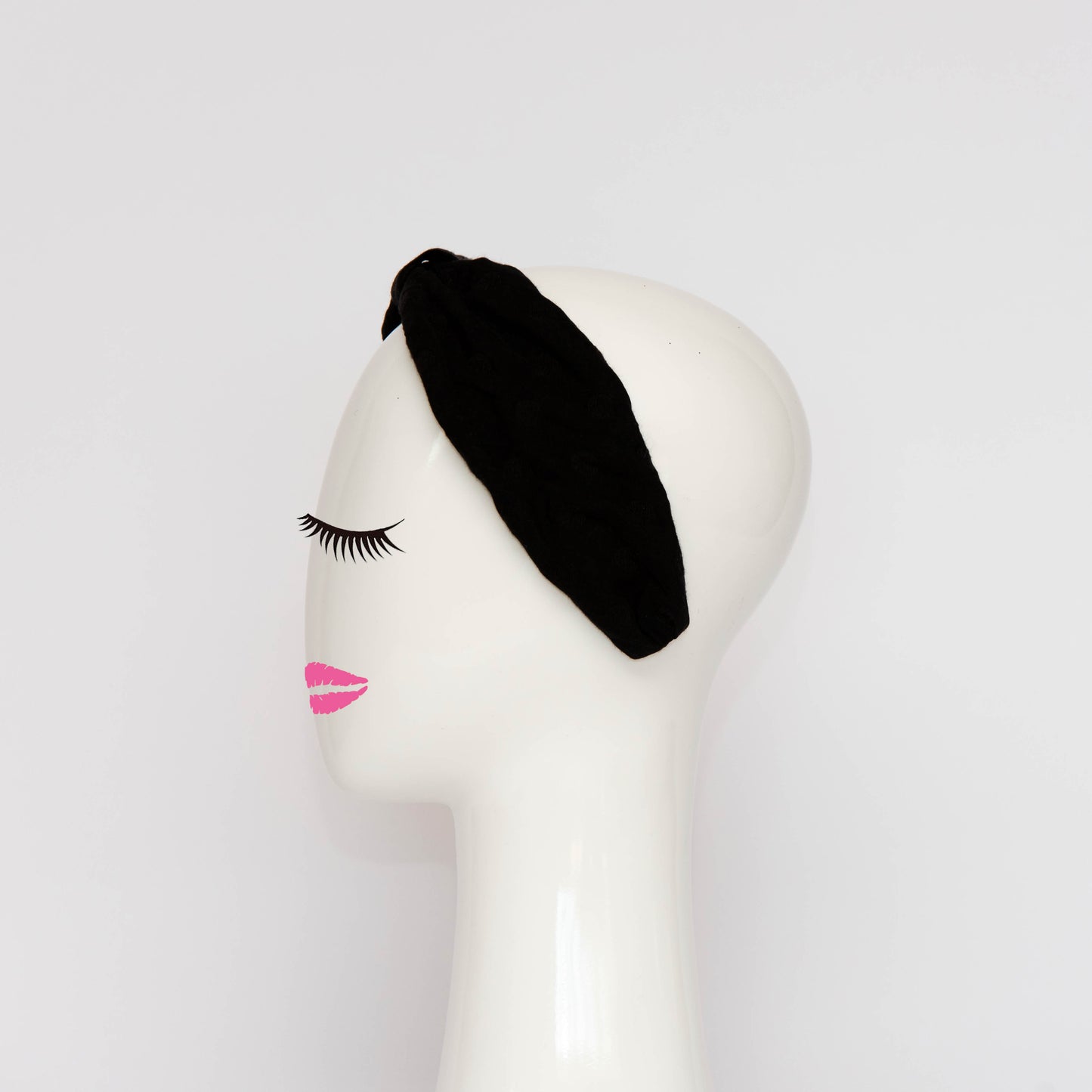 A side view of the Georgie Headband in black. The headband is a hand draped shape that is cinched with a centre wrap. The headpiece is created by Melbourne based Lauren J Ritchie Millinery.