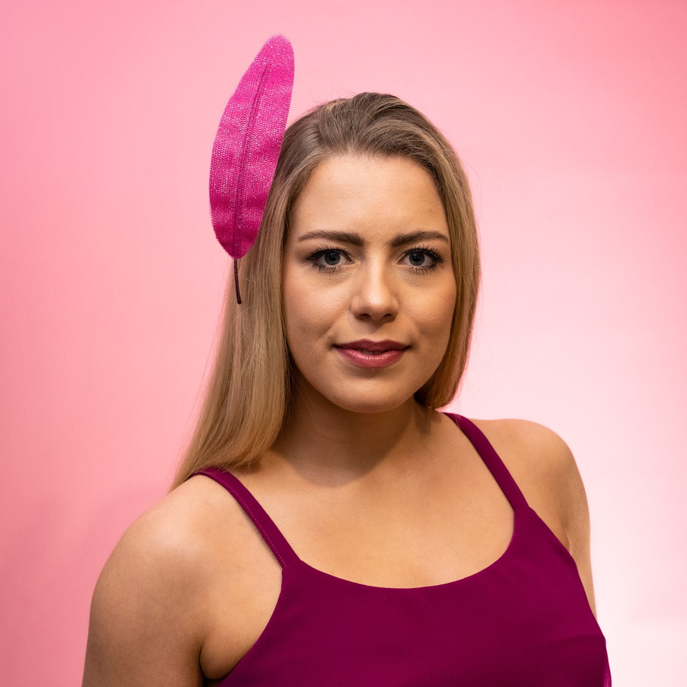 Front view of a model wearing the Alba Headband in magenta, a floating tulle feather, secured to the head using a headband. Created by Melbourne based Lauren J Ritchie Millinery.