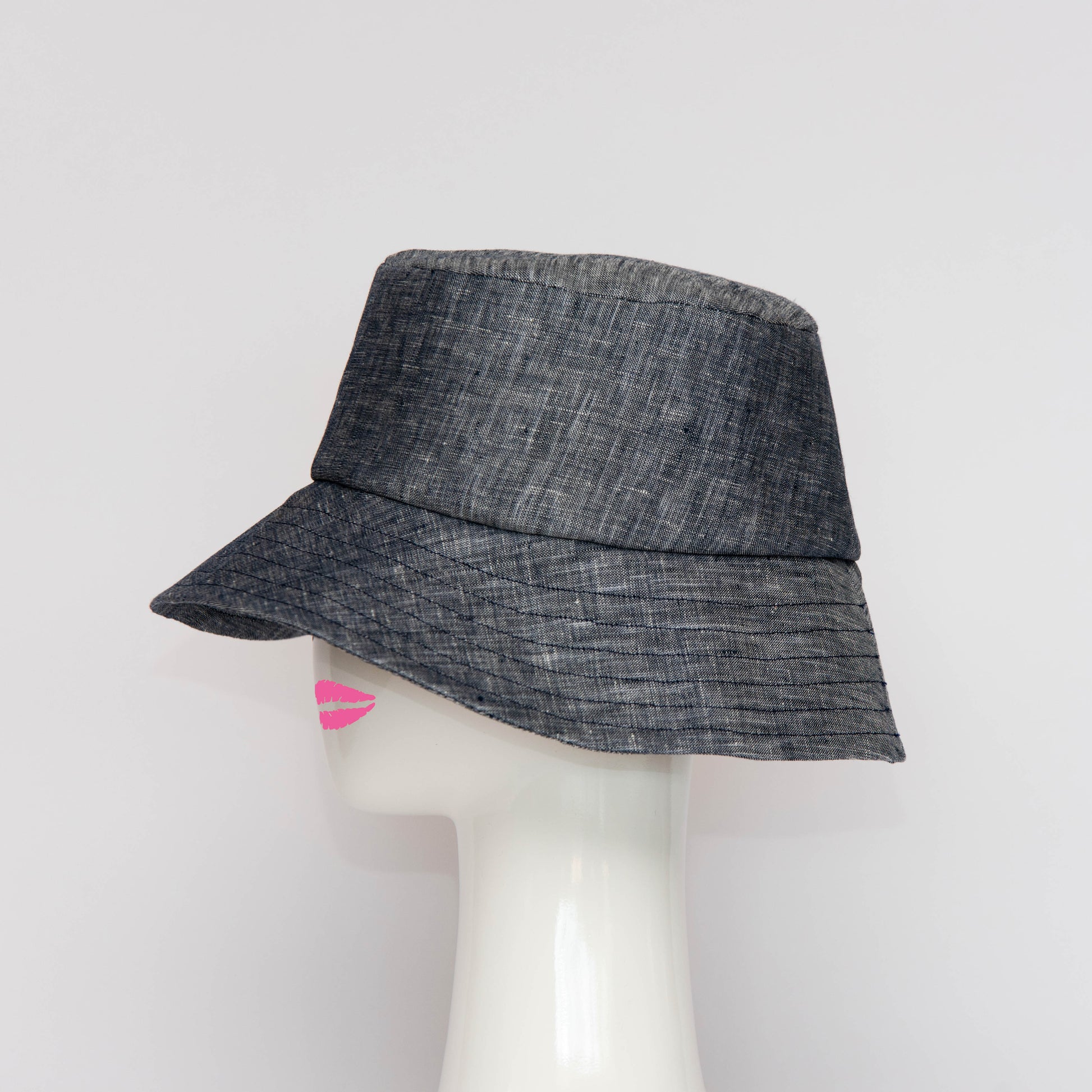 A side view of the Appin Bucket Hat in cotton denim has a square shape crown with tip and side band.  Created by Melbourne based Lauren J Ritchie Millinery.