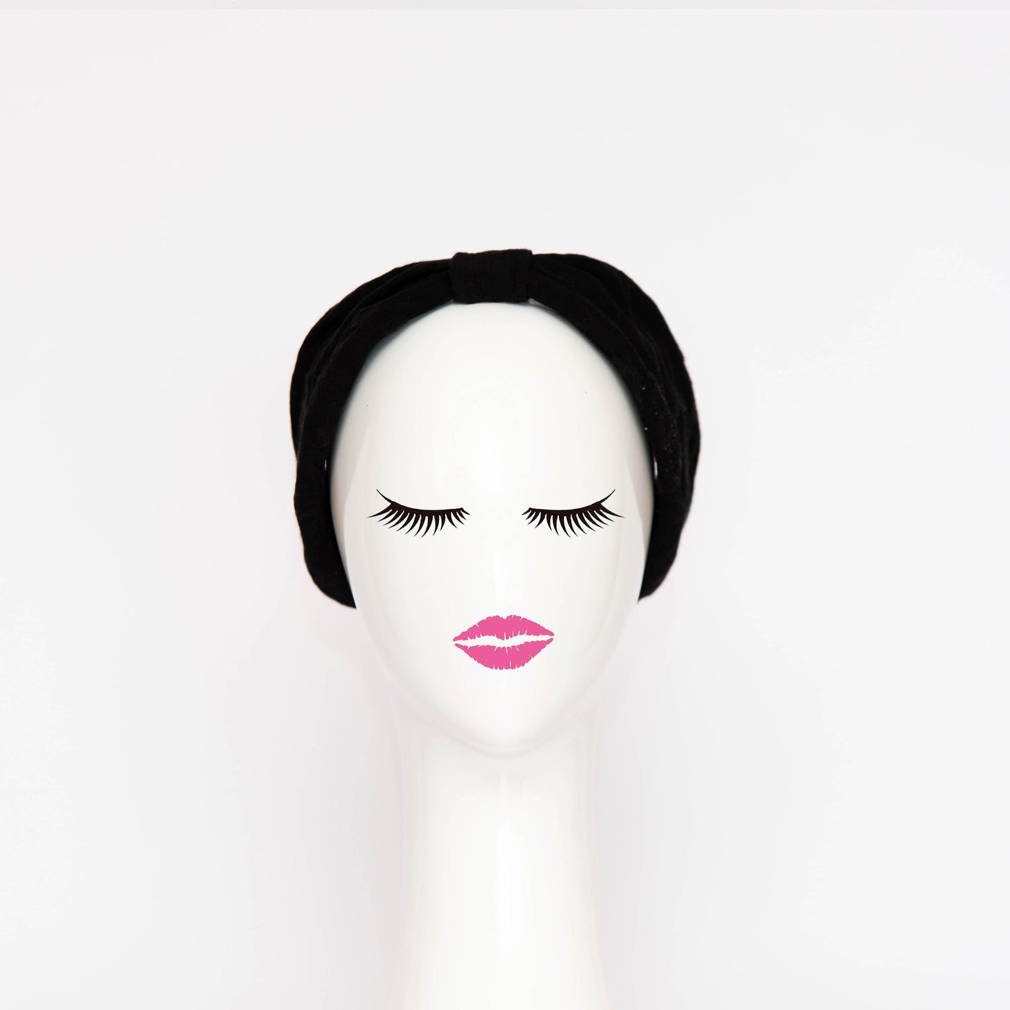 A front view of the Georgie Headband in black. The headband is a hand draped shape that is cinched with a centre wrap.  The headpiece is created by Melbourne based Lauren J Ritchie Millinery.